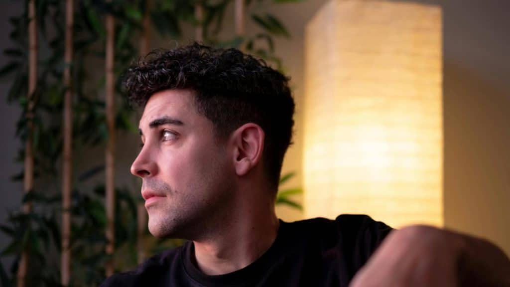 A man looking to the side in soft indoor lighting.
