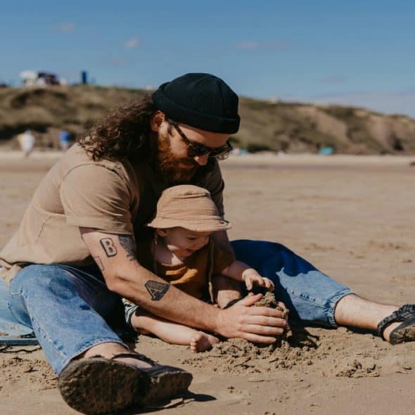 A man playing with a baby by the beach