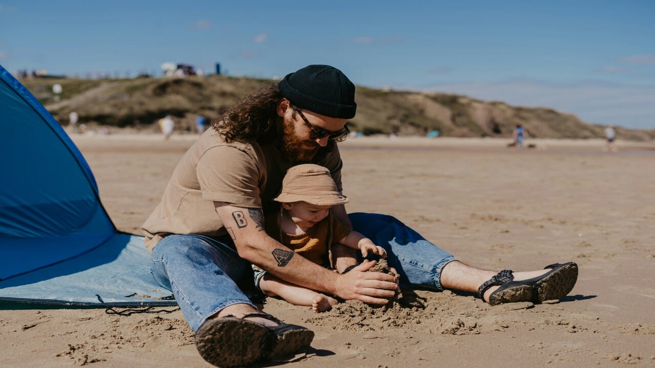 A man playing with a baby by the beach