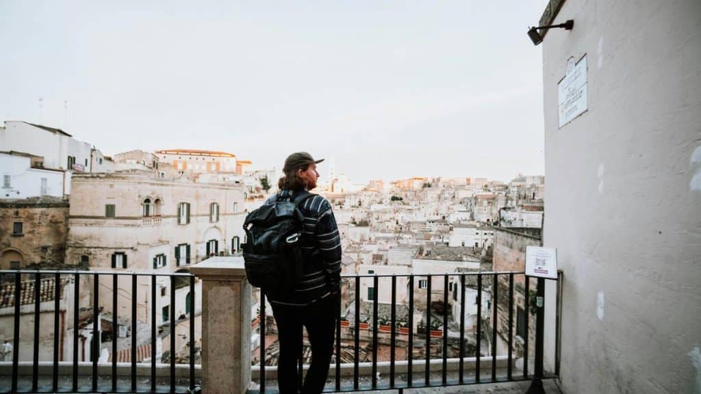 A traveler with a backpack overlooking a historic hillside city.