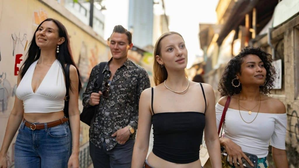 Four young adults walk down an outdoor urban alleyway together during the daytime.