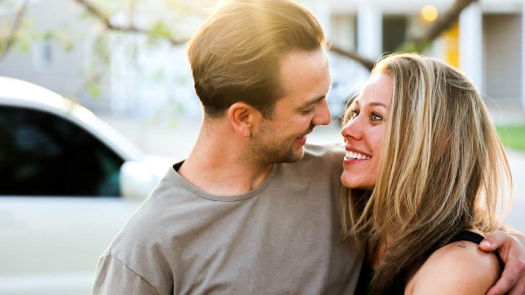 A man and woman looking in the eyes of each other while standing in the sun.