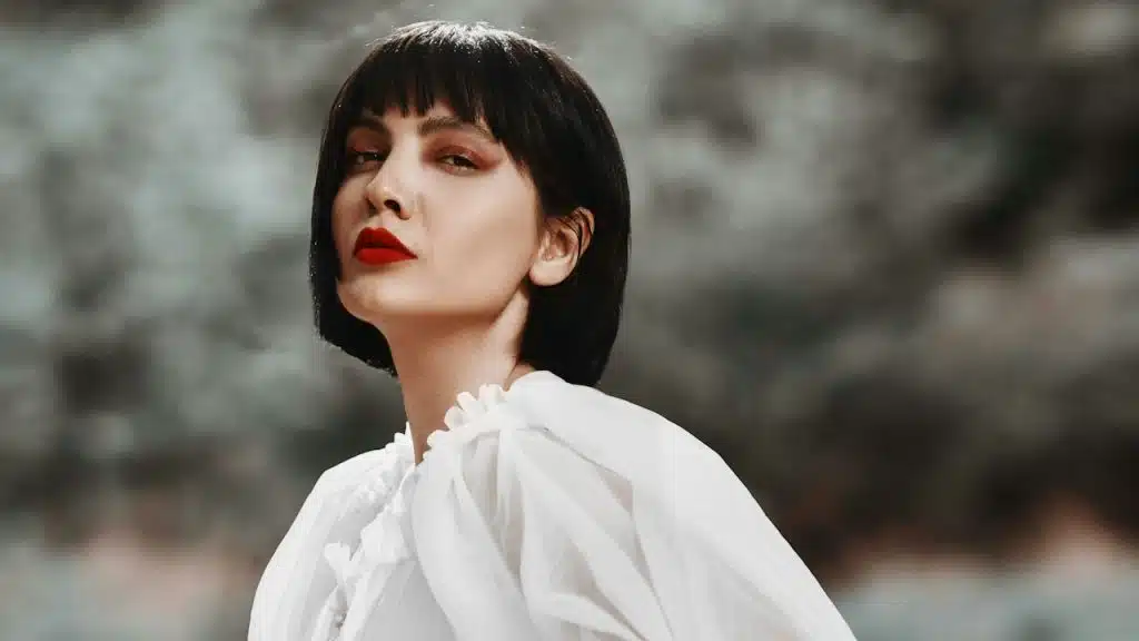 A woman with short hair looking at the camera with a haughty expression.