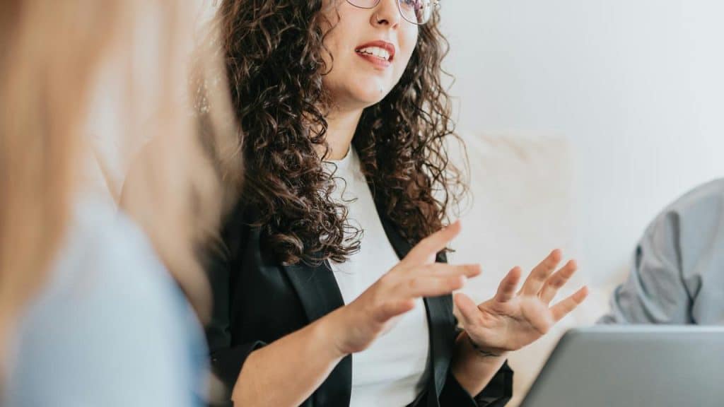A woman gesturing with her hands while explaining something indoors.