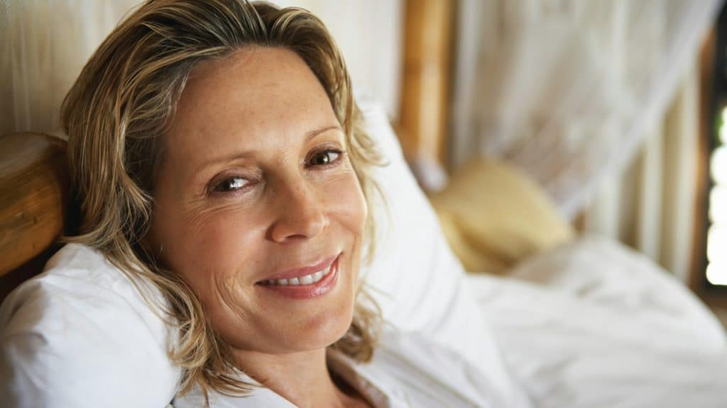 A woman lying on a bed smiling for the camera.