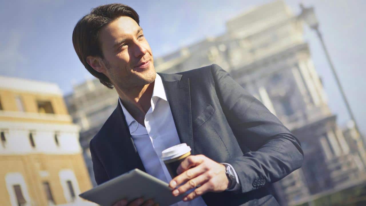 A man holding a coffee cup and tablet.