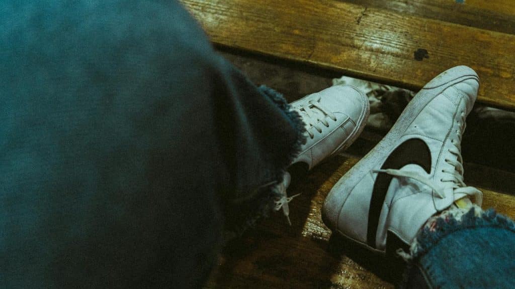 A pair of white sneakers resting on a wooden bench.