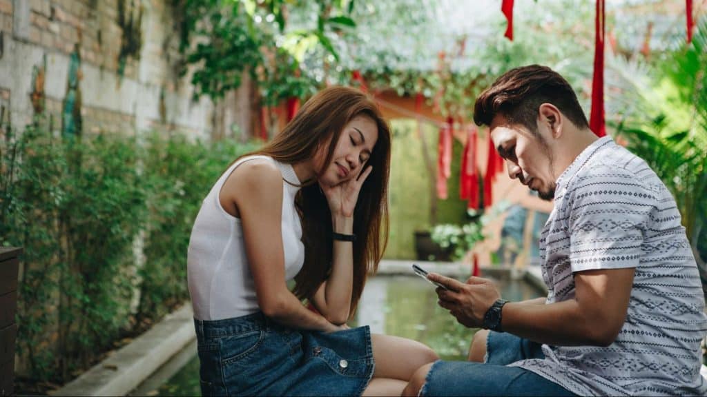 A man busy playing with his phone and a woman disappointed