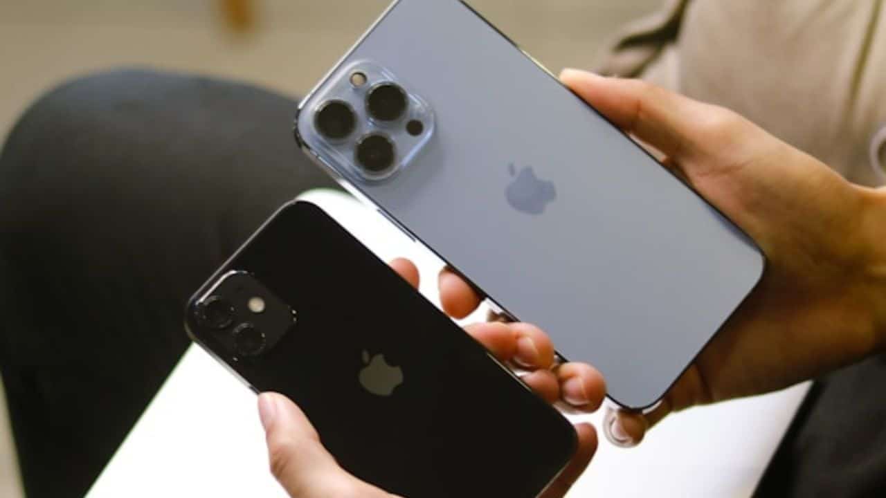 A person holds two different smartphones, one blue and one black, side by side.