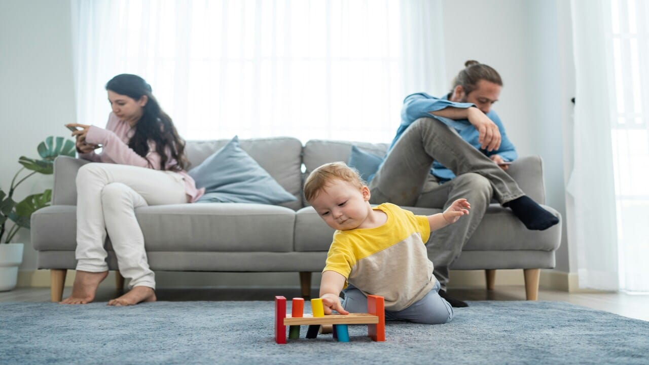 A couple not paying attention to their toddler while using their phones