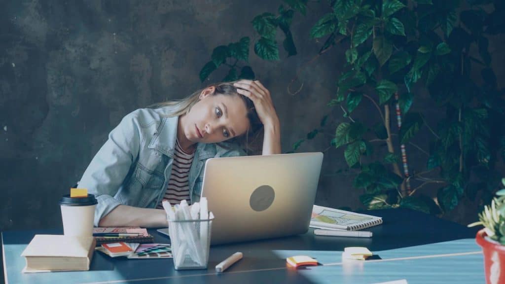 A woman appears stressed while working on a laptop