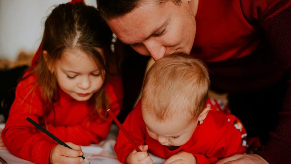 A father drawing with his two young children.
