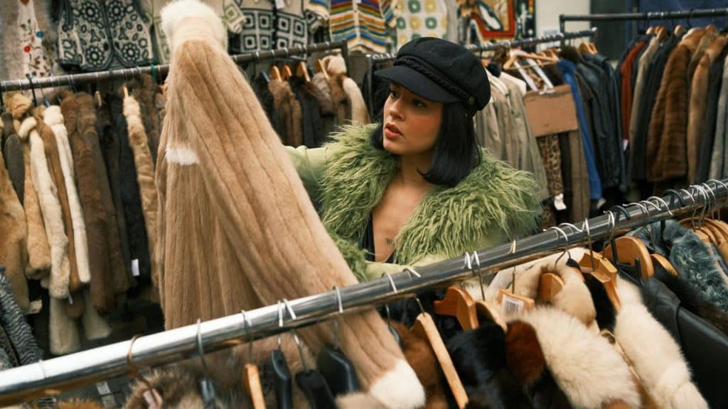 A woman shopping for vintage fur coats at a clothing store.