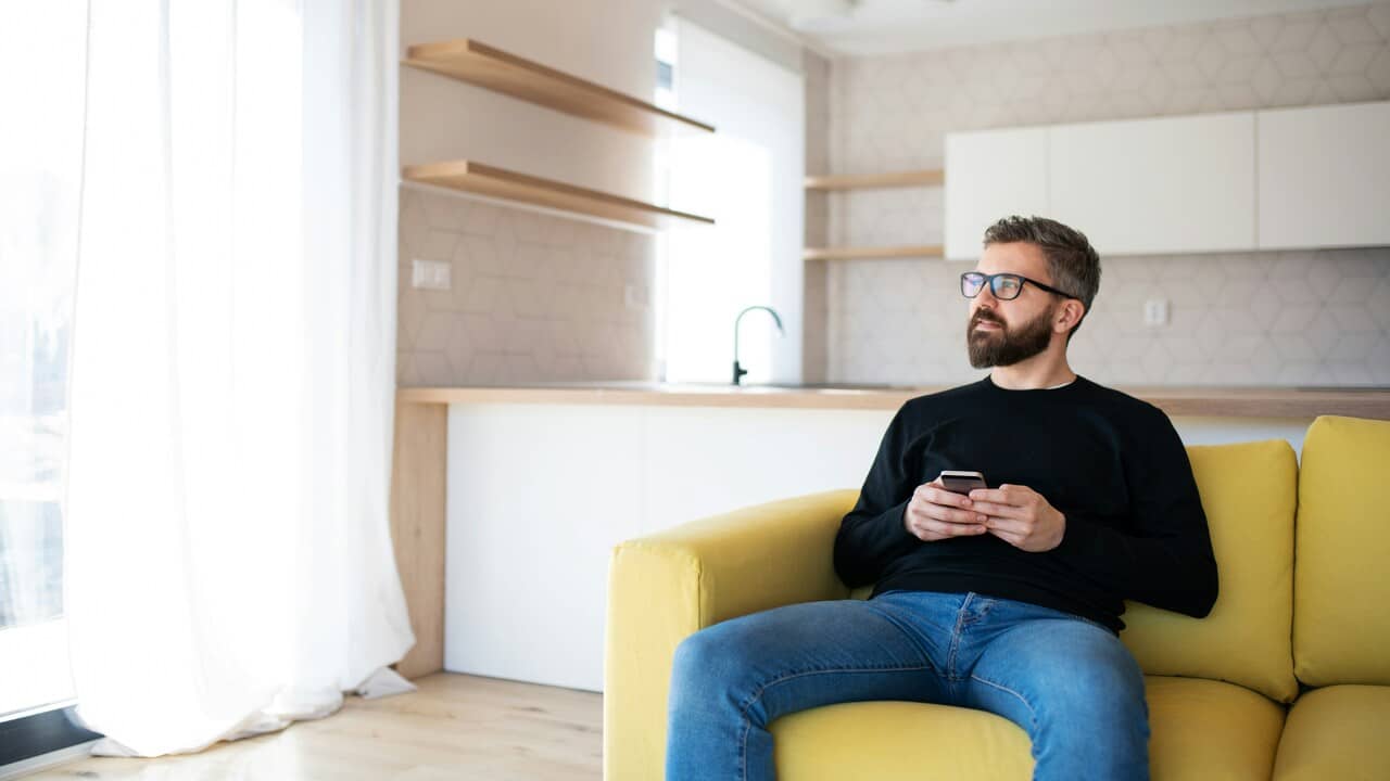 A man sitting on sofa holding his phone