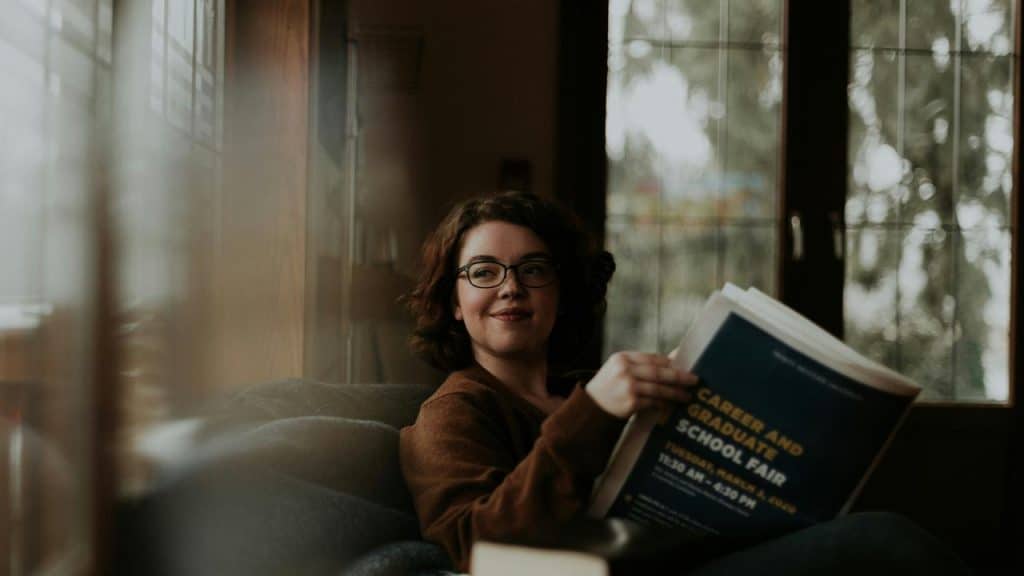 A woman reading a magazine on a couch.