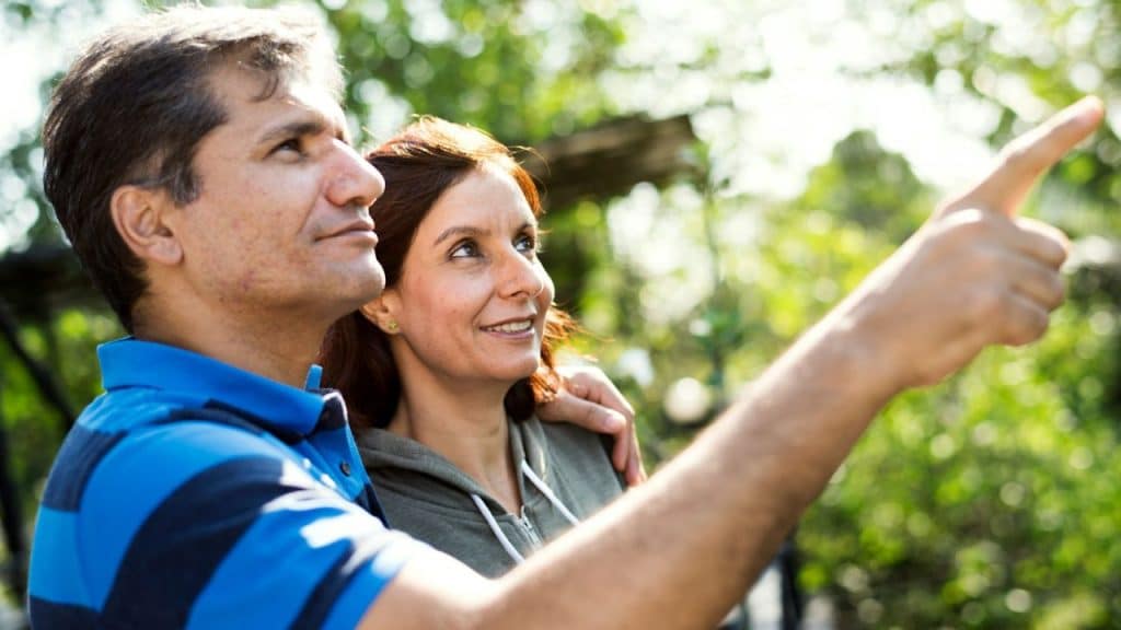 A man points toward the distance while a woman beside him looks in that same direction.