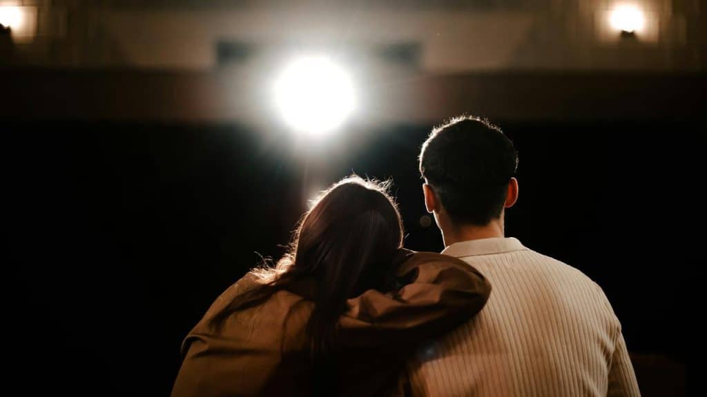 A woman resting her head on a man’s shoulder while watching a show.
