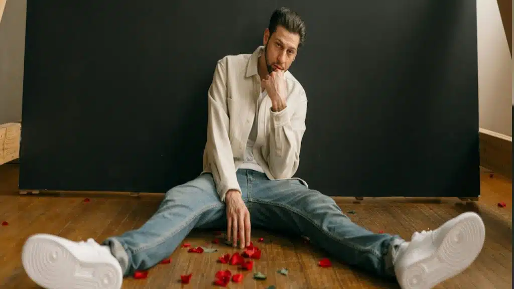 A man sitting on the floor in front of a chalkboard with rose petals spread on the floor.