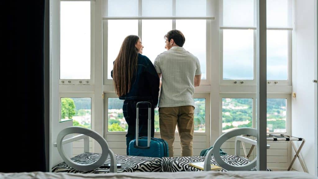 A couple with suitcases looking out a window.