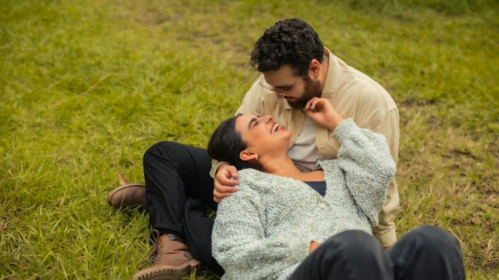 A man and a woman lying together in the grass.