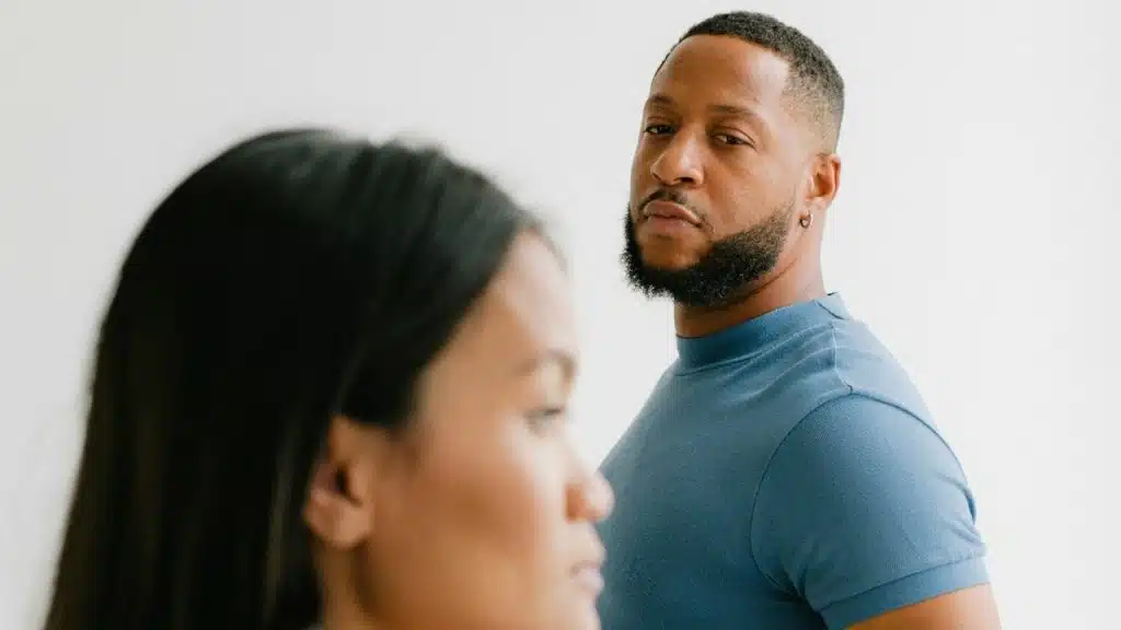 A man with a beard looks toward a woman whose face is partially out of focus.