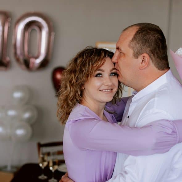 A man and a woman embracing each other at their 10th wedding anniversary.