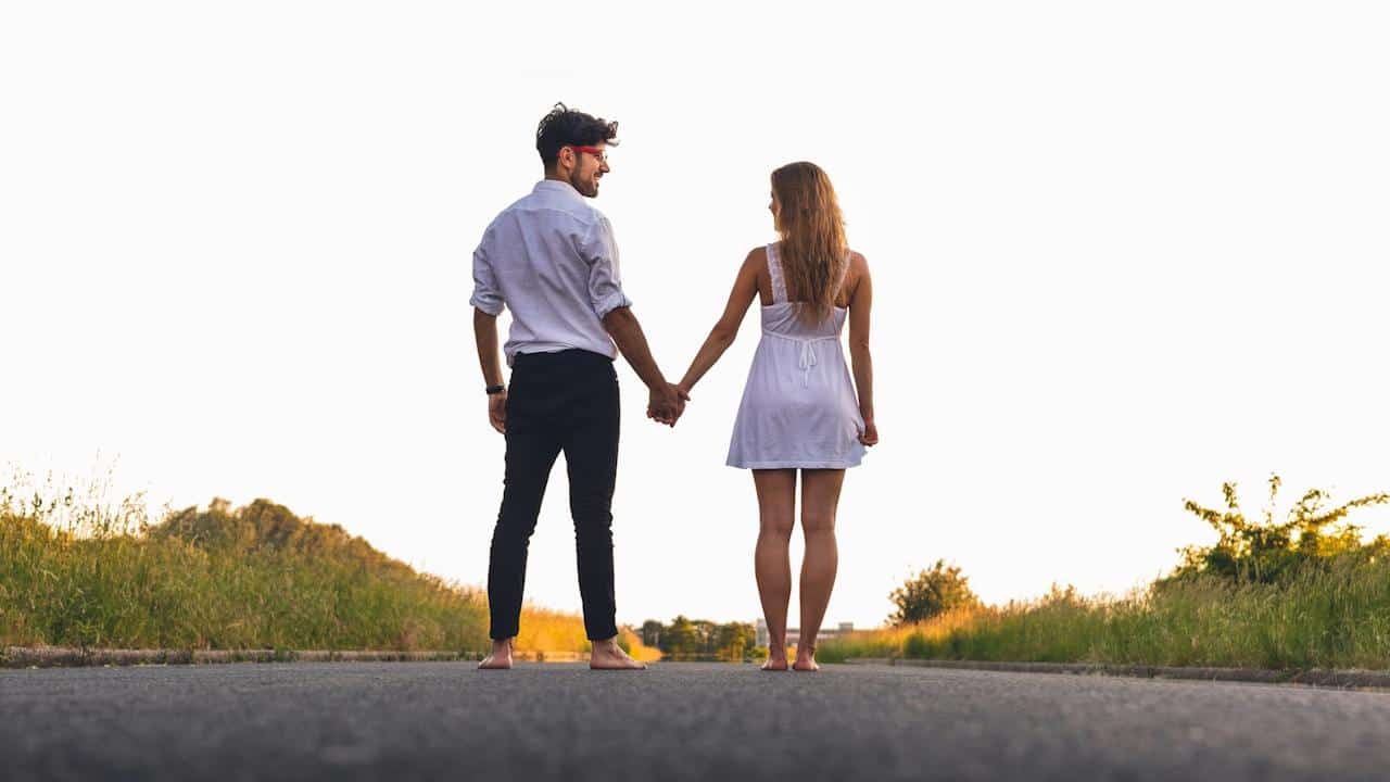A man and a woman stand barefoot on a paved