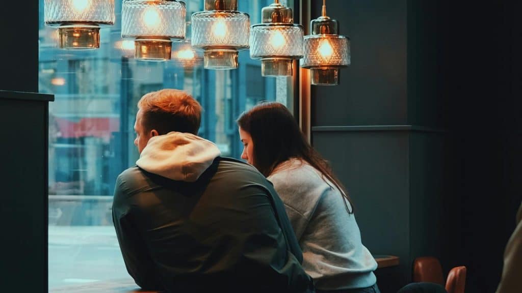 A couple sitting quietly together by a café window.