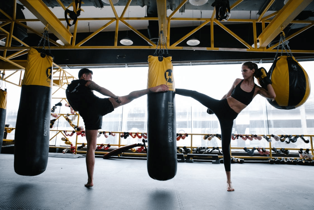A man and a woman kicking a punching bag