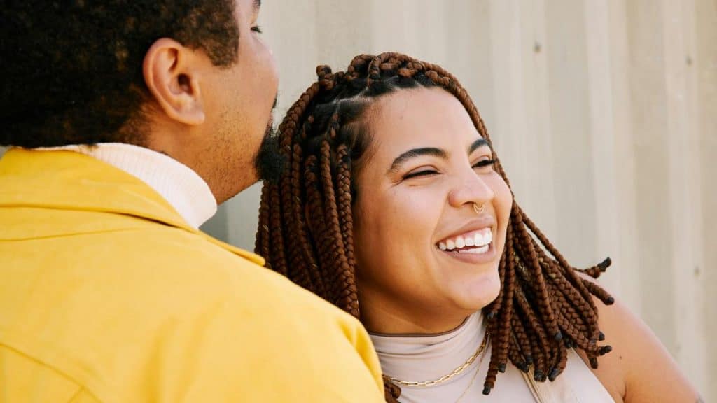 A woman laughing joyfully while standing close to a partner outdoors.