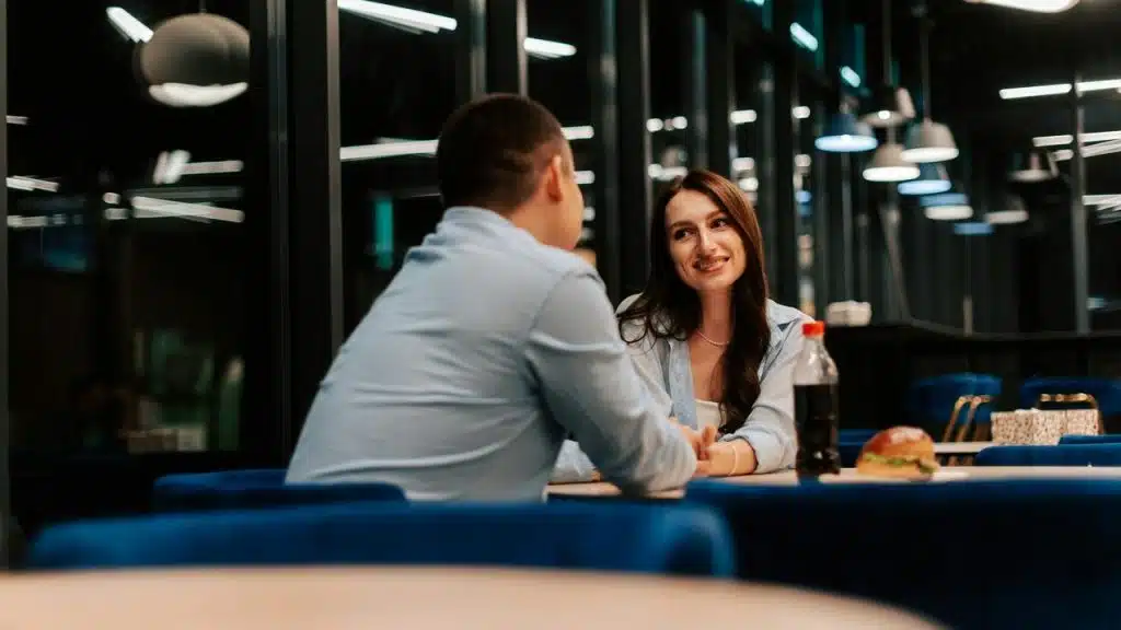 A woman smiling at a man during a casual dinner conversation.