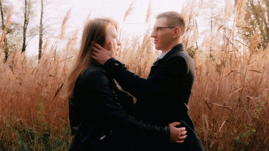 A couple standing in a field and holding each other close.