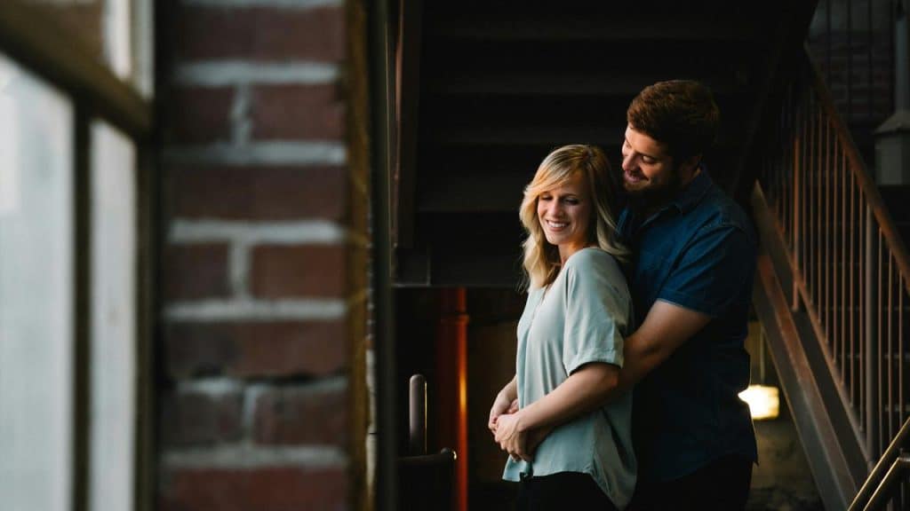 A couple smiling and embracing each other on a stairway.