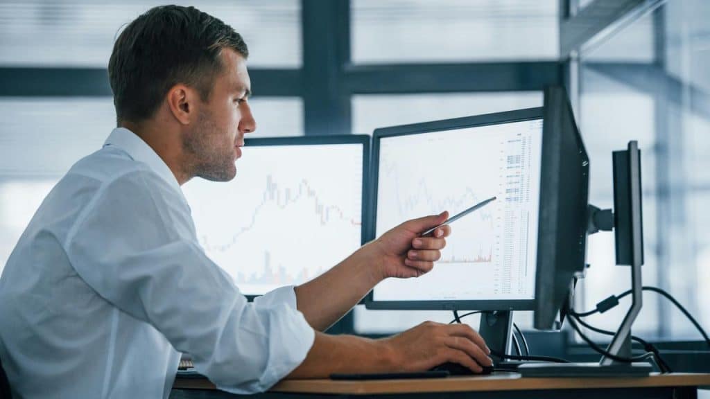 A man analyzing stock charts on computer screens.