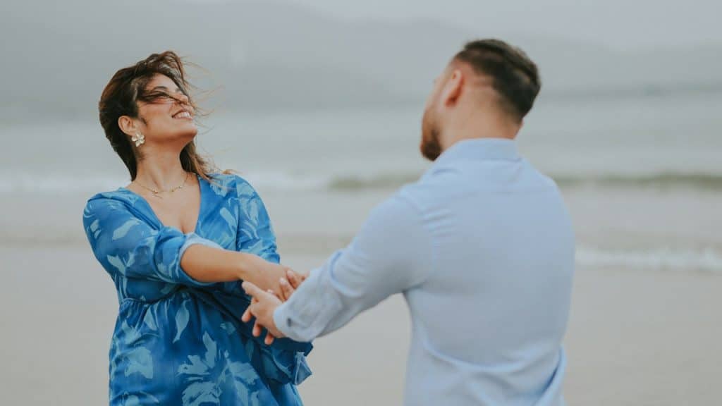 A couple holding hands and dancing on the beach.