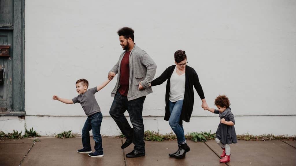 A man and woman walking while holding their children