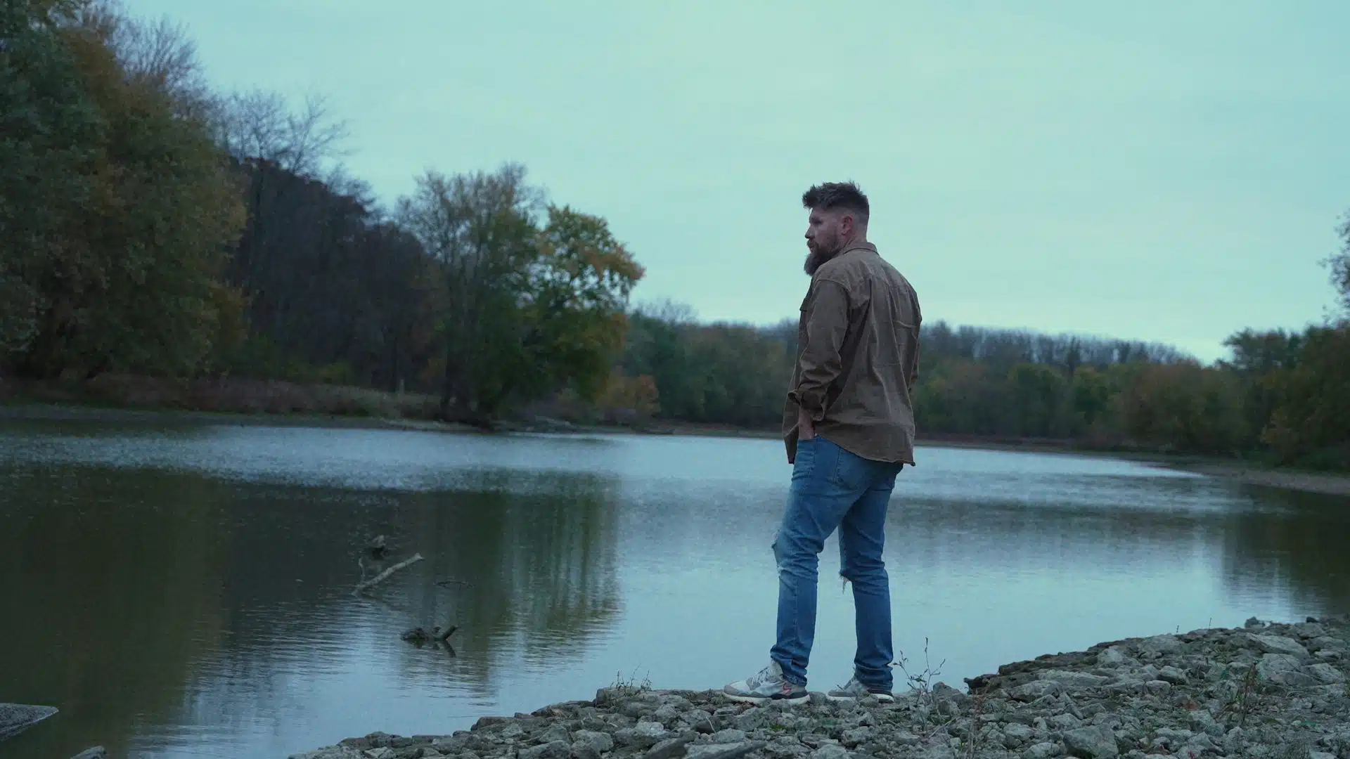 A man standing by the shore and staring at something