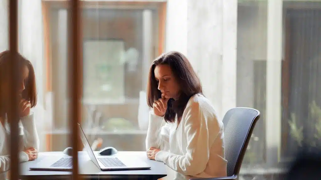 A woman sitting at a desk working on a laptop in an office.