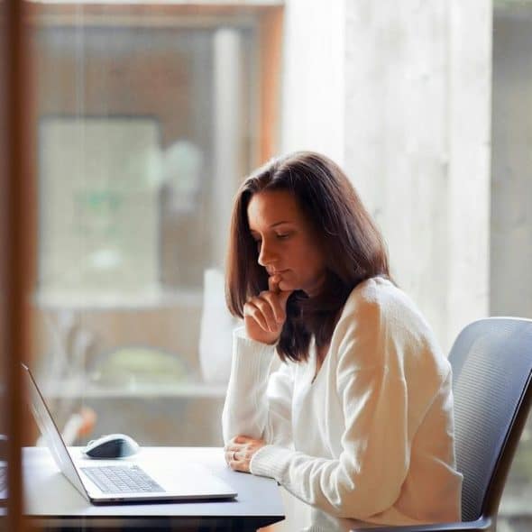 A woman sitting at a desk working on a laptop in an office.