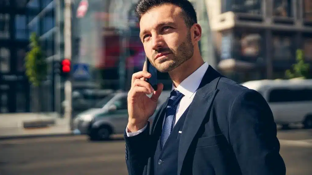 A man in a suit talking on a phone outdoors.