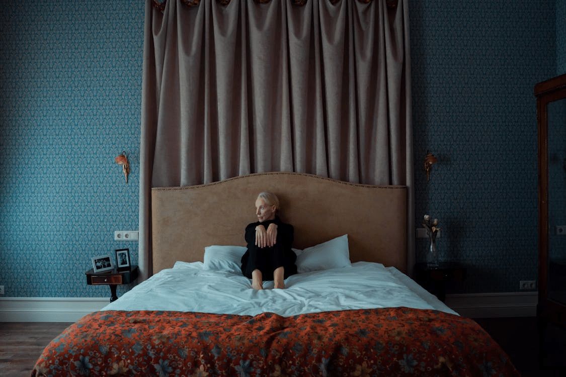Mature woman sitting on bed, looking sad