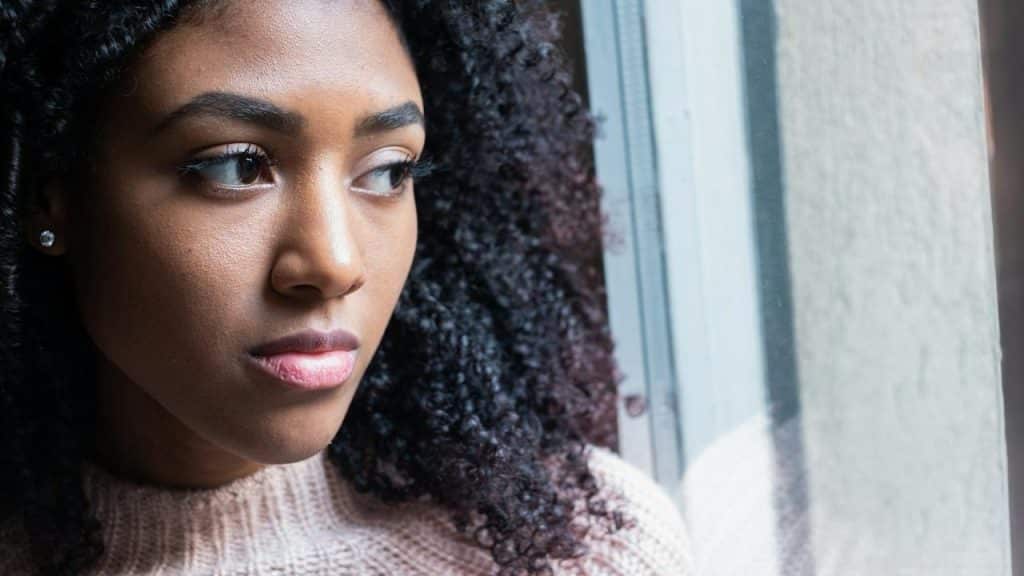 A woman gazing out a window with a thoughtful expression.