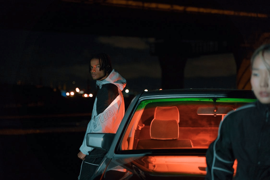Unhappy couple leaning on car at night