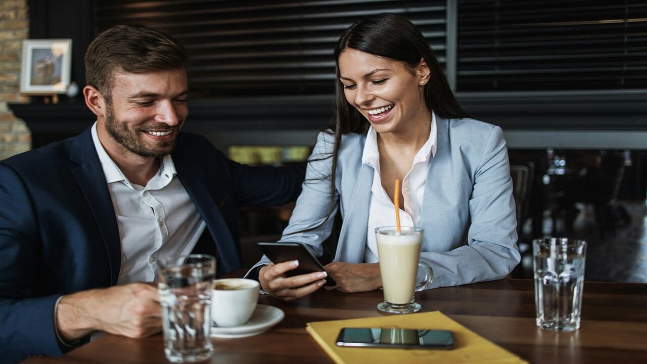 A woman checking her phone while in a restaurant with her husband