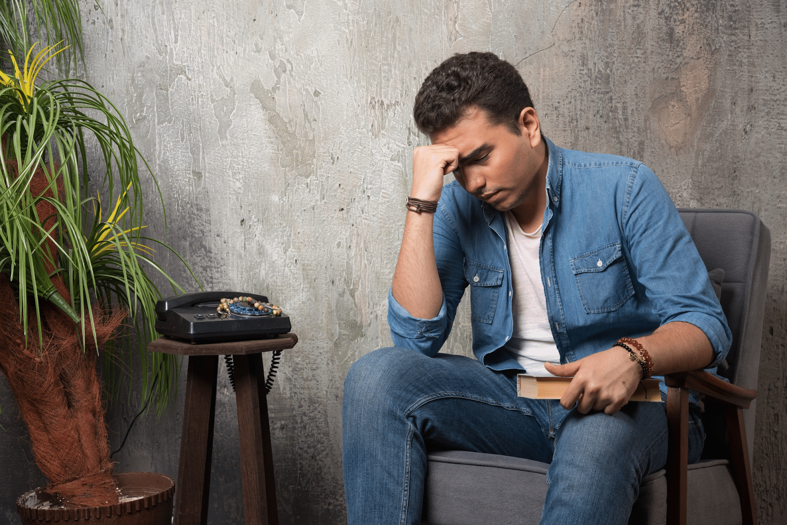 Thoughtful man sitting on chair with book
