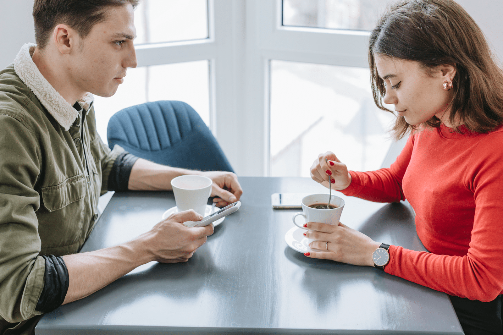 Couple having coffee in restaurant, one partner withdrawn from conversation