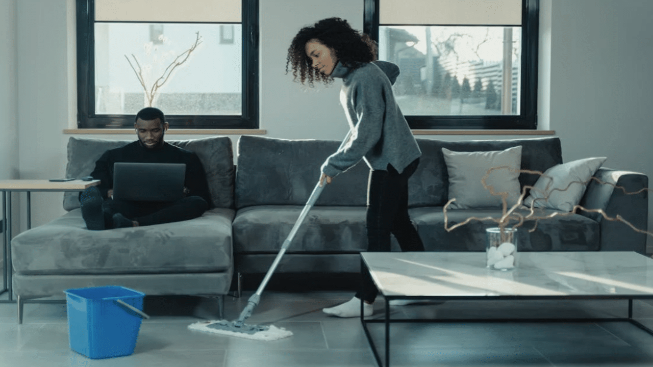 A woman mopping while her husband works