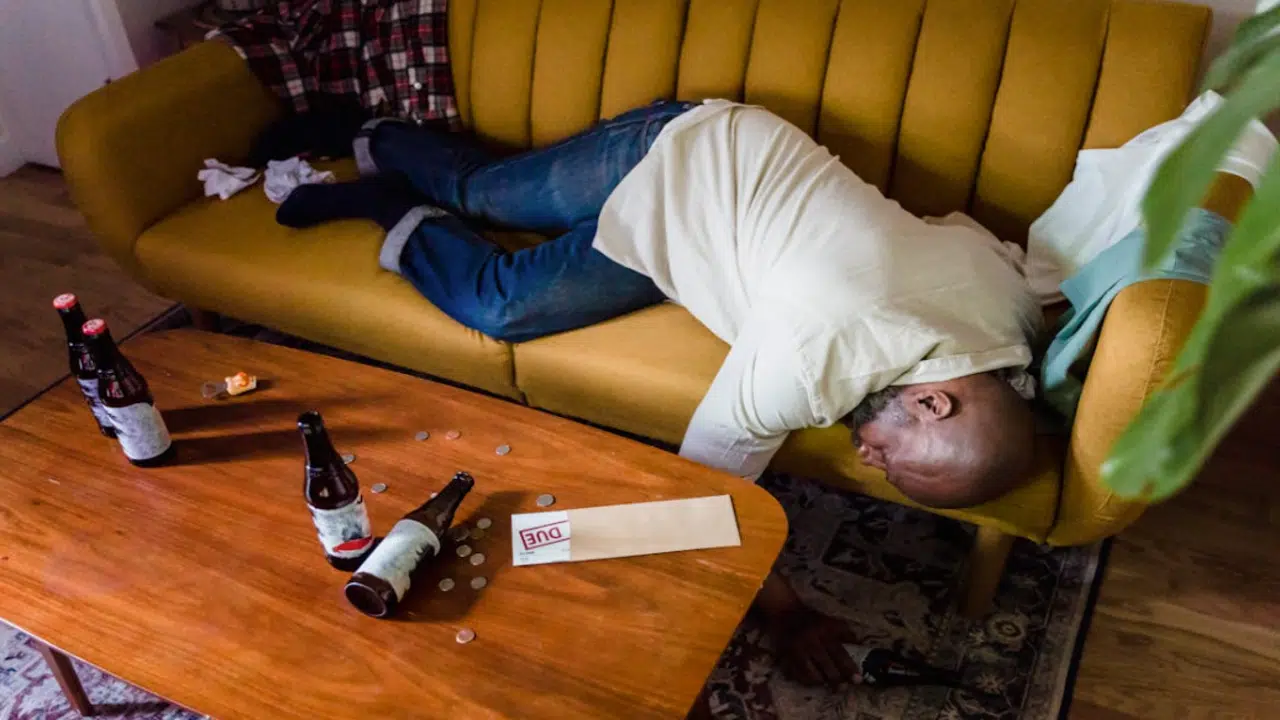A man sleeping on the couch due to drunkenness