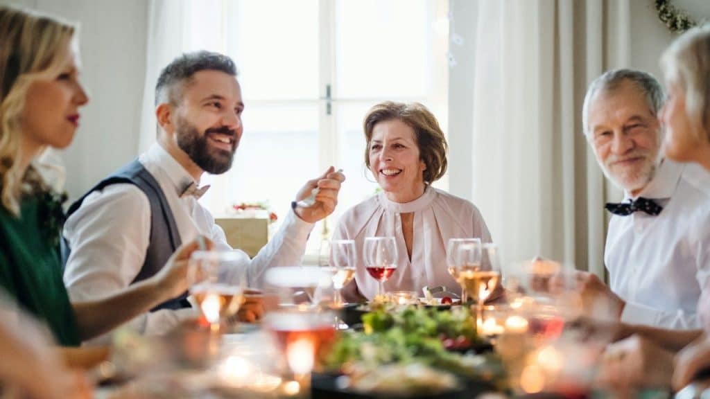 A group of people in formal attire sits around a dinner table laughing and talking.