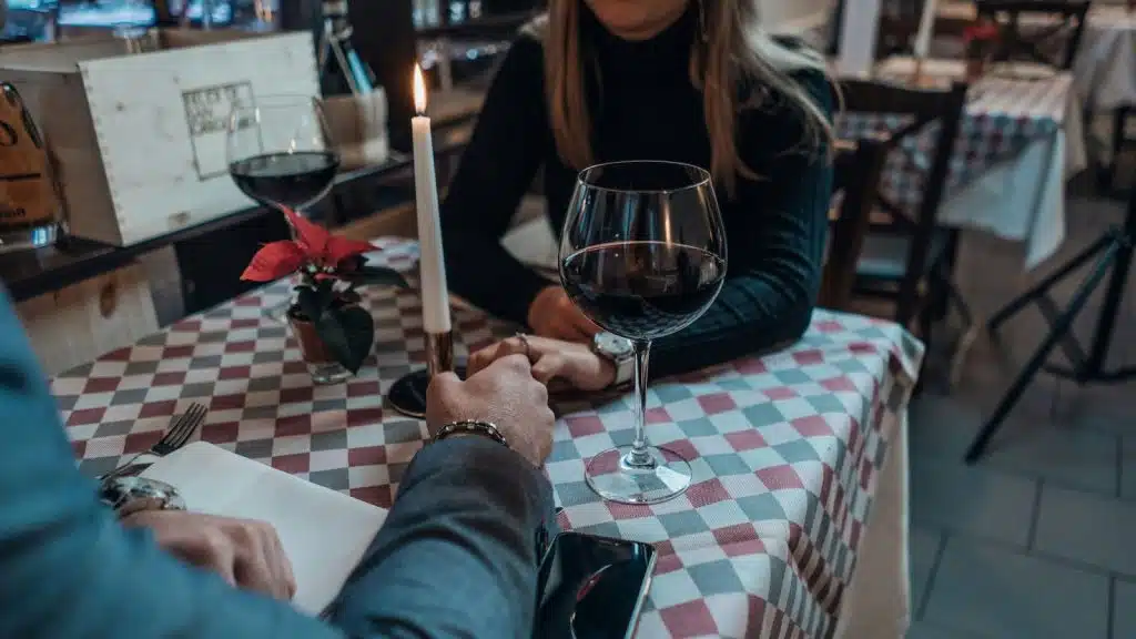 A man and woman holding hands while having dinner